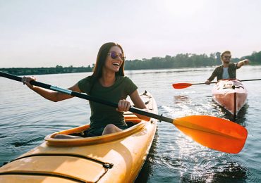 Beautiful young couple kayaking on lake together and smiling